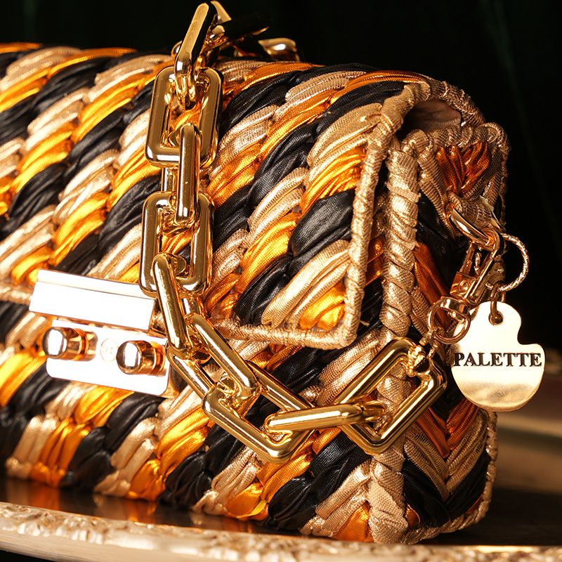 Gold and black braided handbag with gold chain and 'PALETTE' tag on a dark background