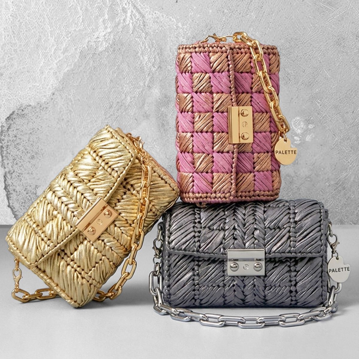 Three woven handcrafted handbags in gold, pink, and gray on a grey surface with a textured white background - Palette by Rishma 