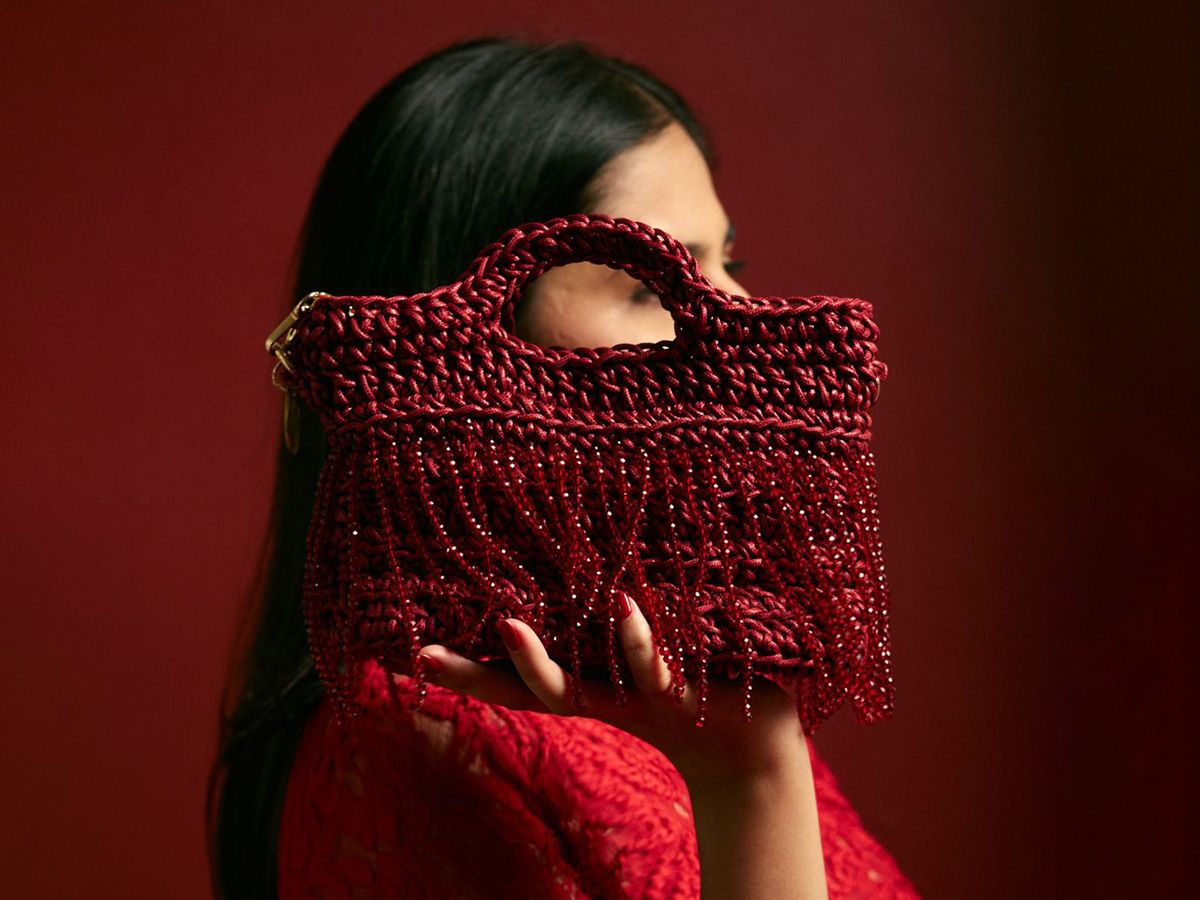 Person holding a red crochet bag with crystal beads against a red background - Palette by Rishma 